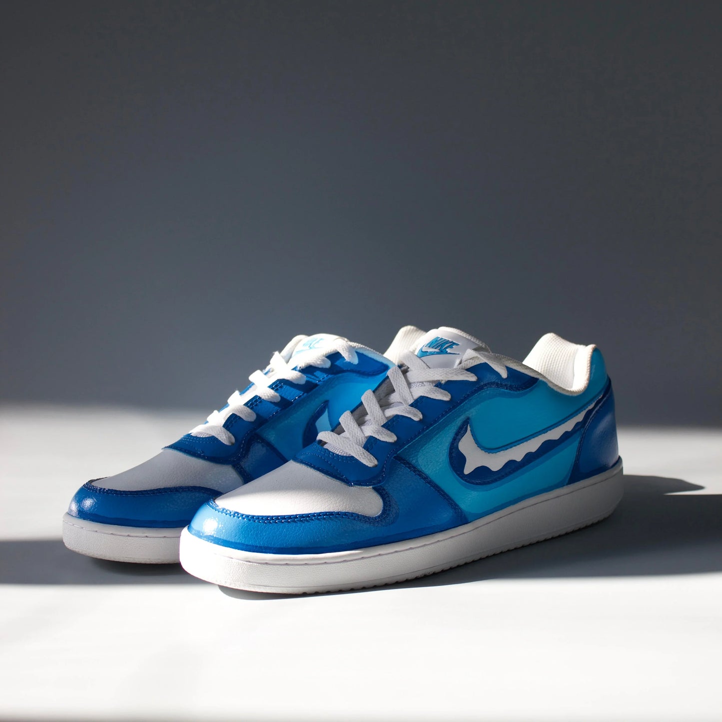 hand-painted Blue and white sneakers inspired by oceanic design with a prominent Nike logo on a gray background