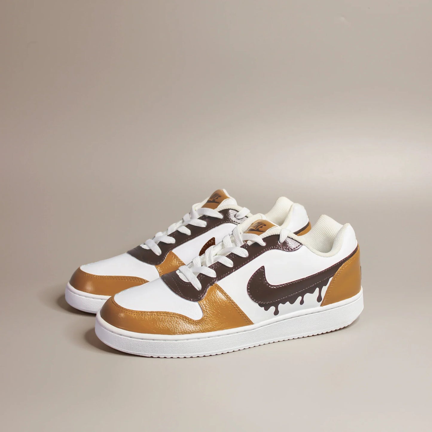 A pair of white Nike sneakers with a unique coffee-inspired design on a beige background