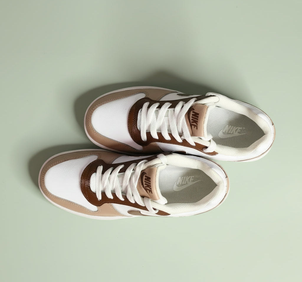 A hand-painted Pair of Nike sneakers with brown and beige design on a light green background