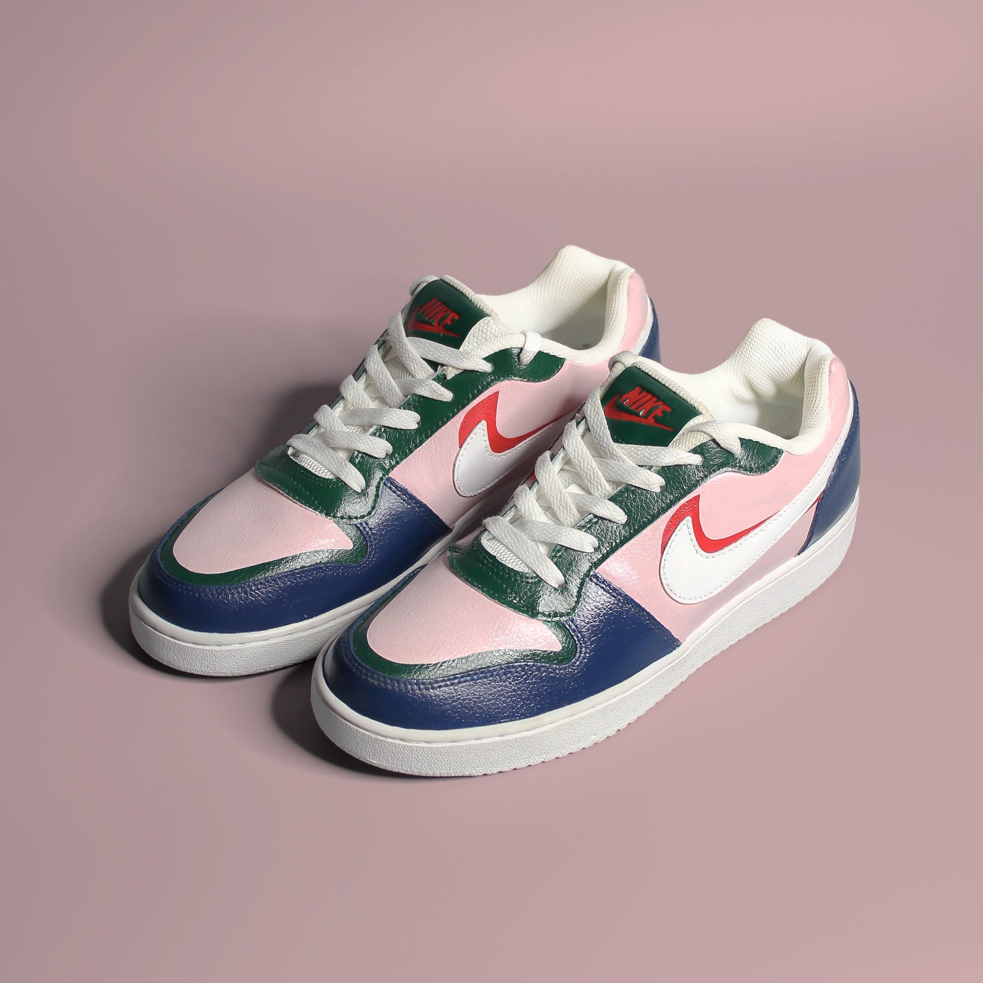 Pair of colourful (blue, green, pink and red) sneakers with a Nike logo on a pink background