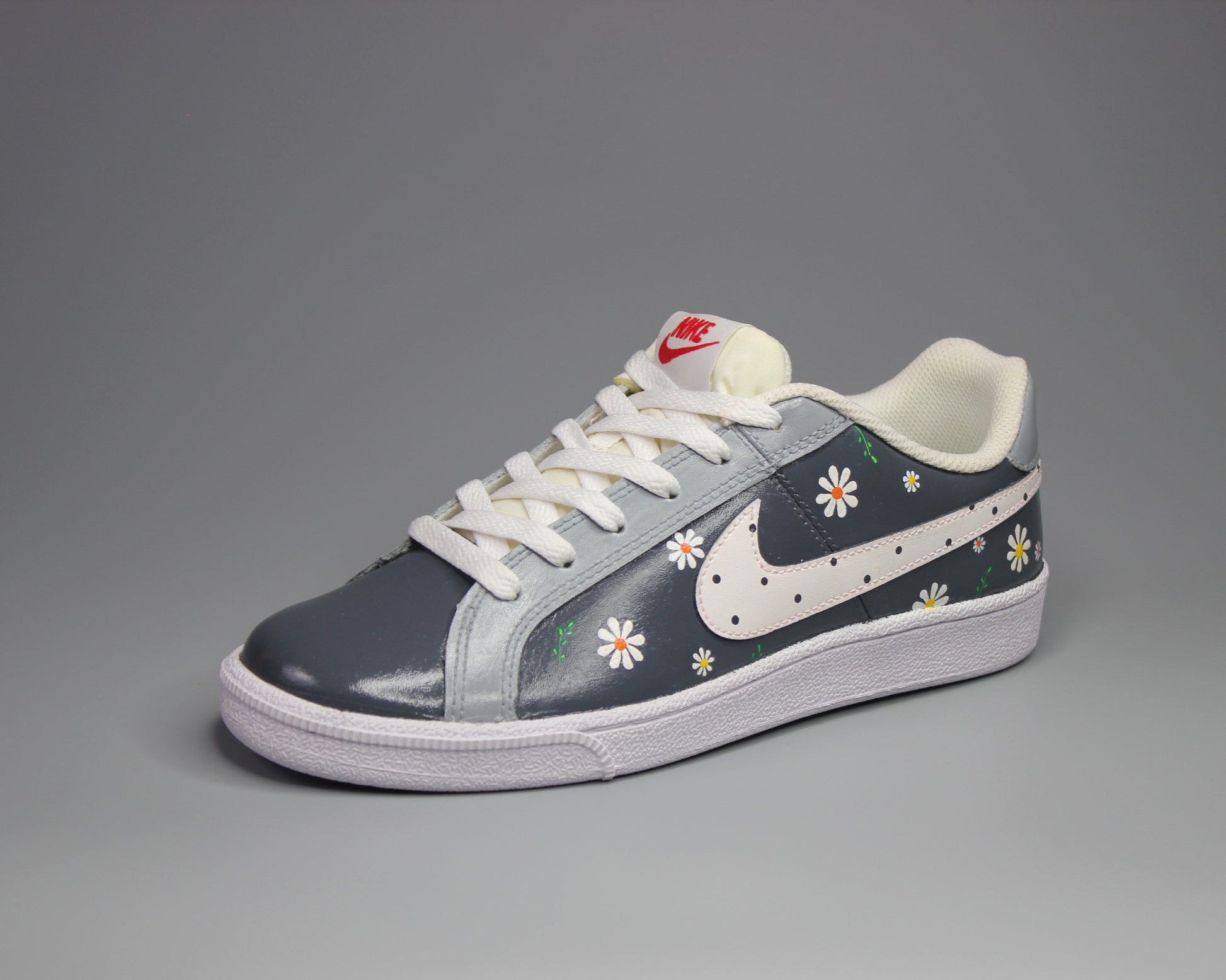 Hand painted pair of Nike sneakers with floral design on a gray background 