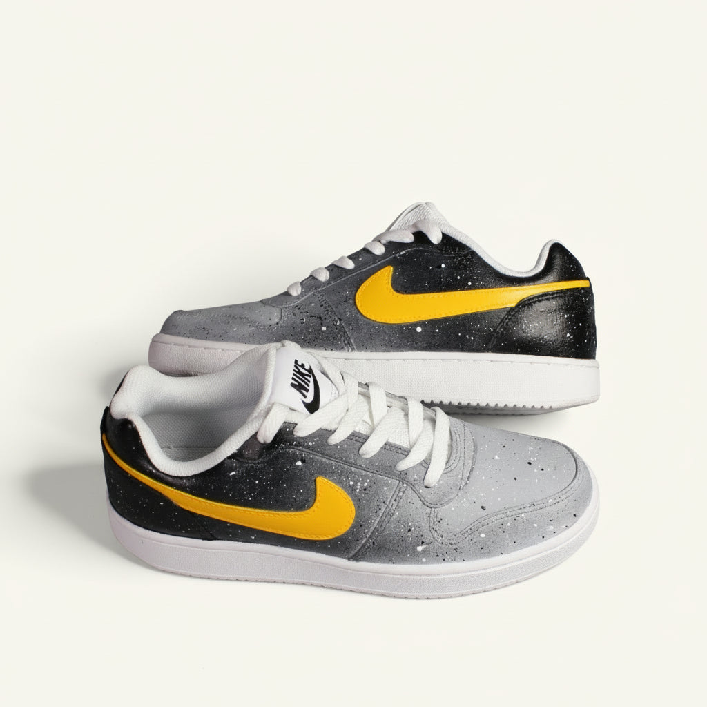 hand-painted Gray sneaker with yellow and black accents representing starts with  the sun on a white background