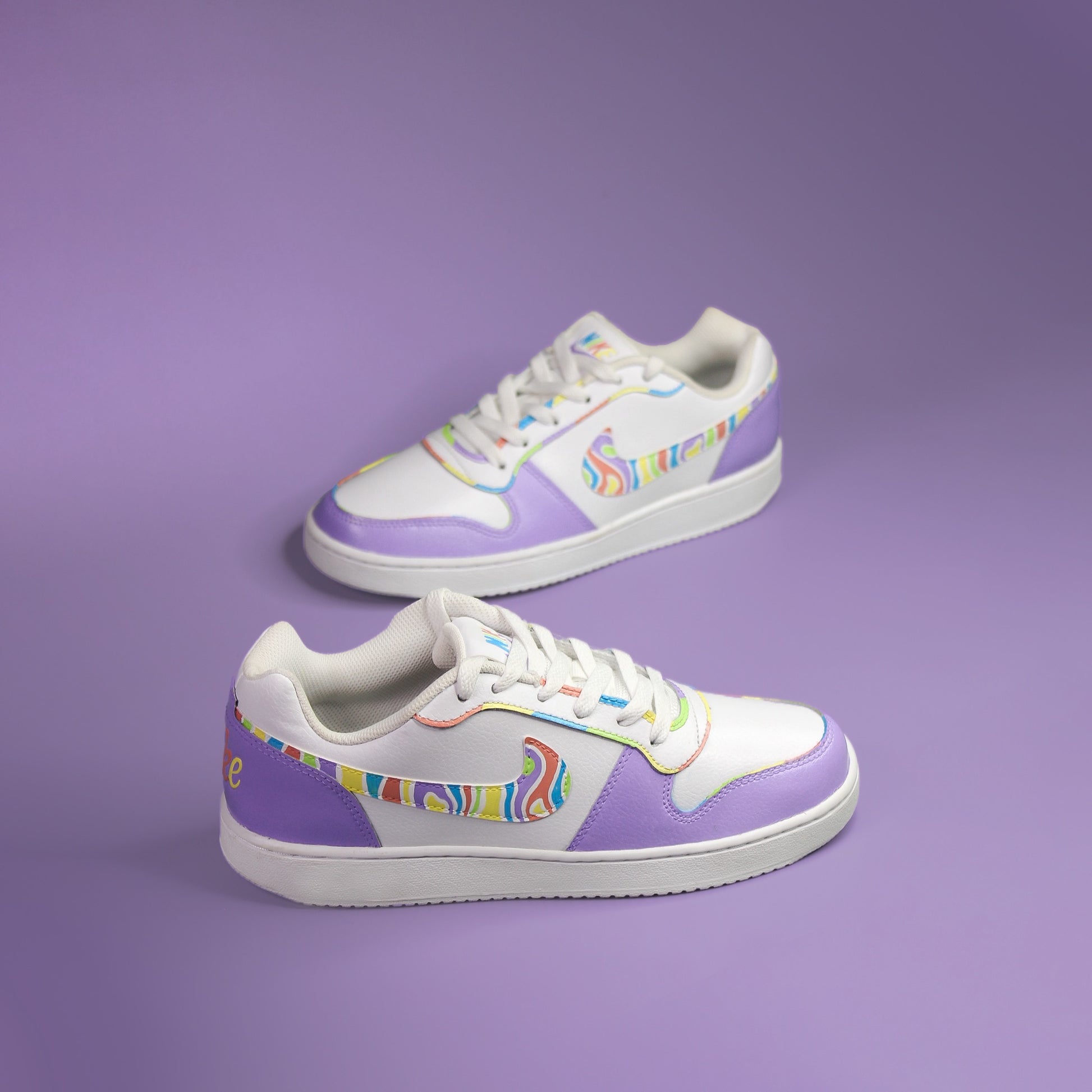 Pair of Nike white sneakers hand-painted in purple with colourful accents on a purple background